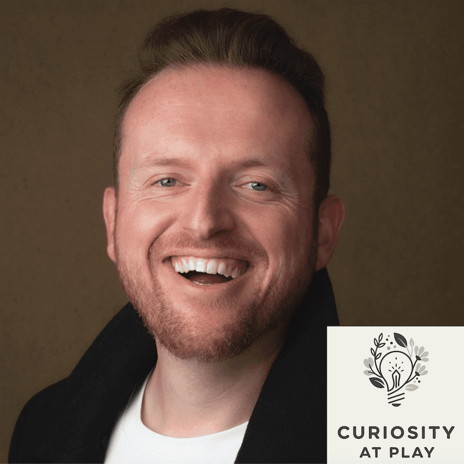 Smiling man with a beard wearing a black jacket, featuring the Curiosity at Play logo.